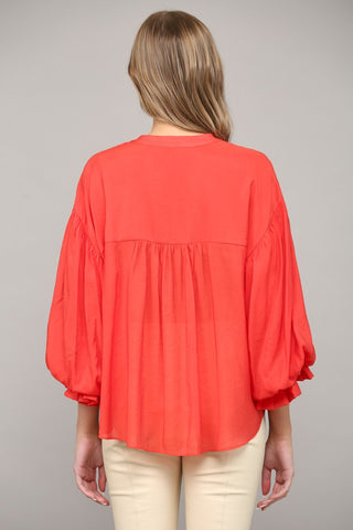 Women wearing a red blouse with blue jeans on a grey background.