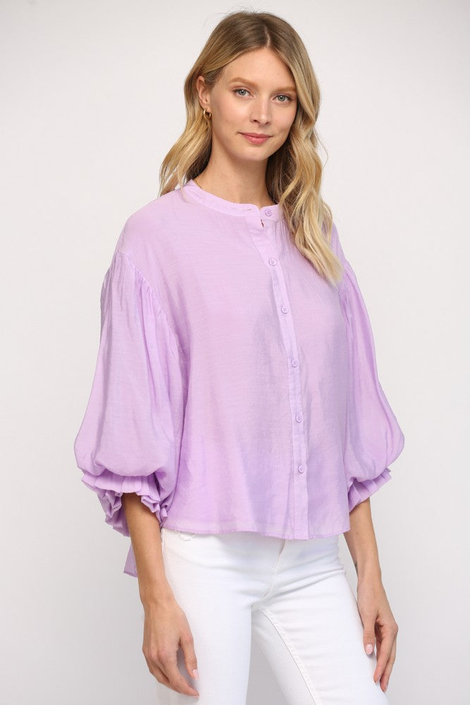 Women wearing a lavender blouse with blue jeans on a grey background.