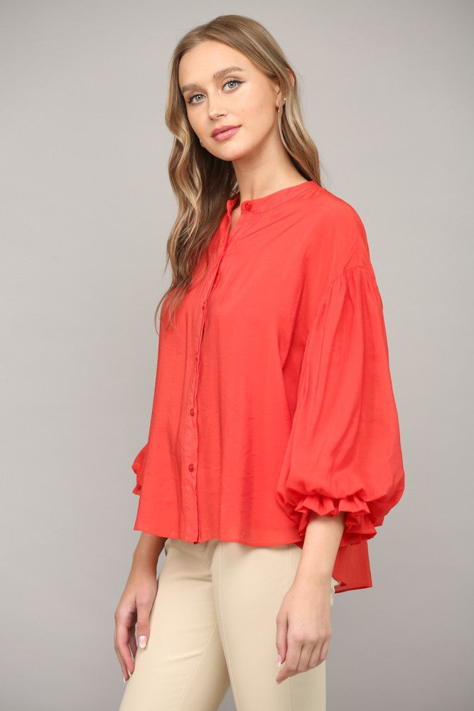 Women wearing a red blouse with blue jeans on a grey background.