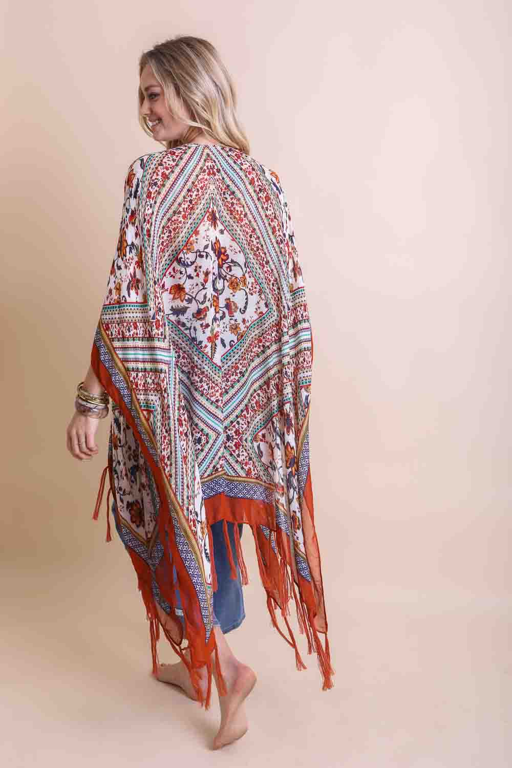 Woman wearing a patterned shawl with fringes on a beige background