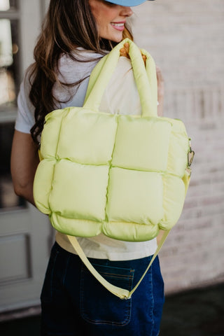 Person holding a bright yellow quilted bag indoors