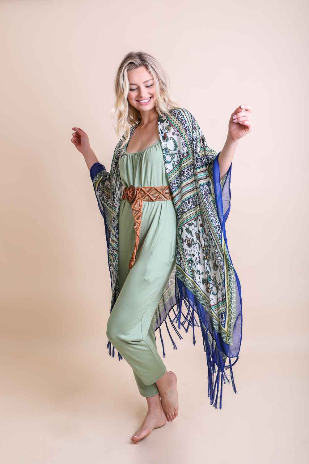 Woman wearing a patterned shawl with fringes on a beige background