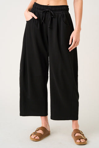 Person wearing black wide-leg pants on a plain background