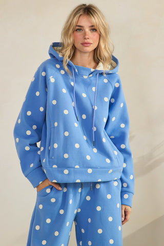 Person wearing a blue hoodie with white polka dots on a plain background