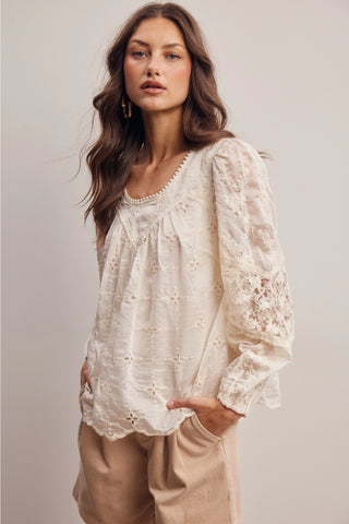 Woman wearing a lace blouse with long sleeves on a plain background
