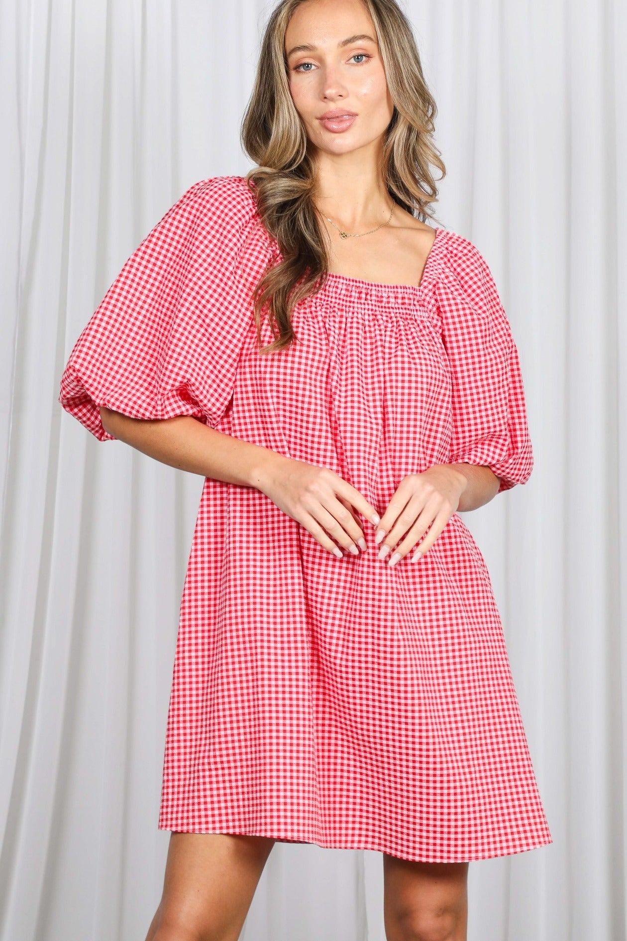 Woman wearing a red and white checkered dress against a plain background