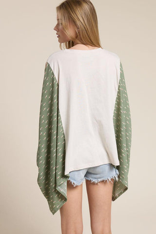 Woman wearing a white top and green patterned kimono-style garment on a beige background