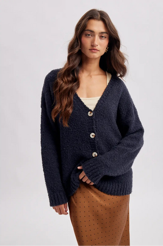 Women wearing a navy cardigan against a neutral background.