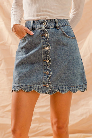 Denim skirt with button details worn by a person on a plain background