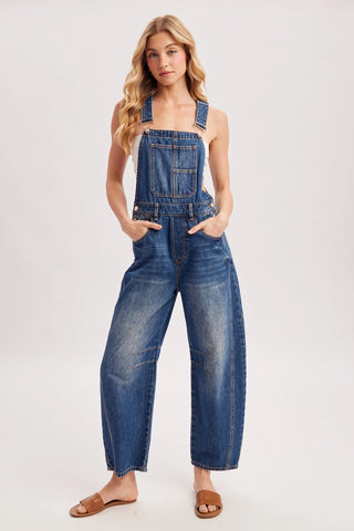 Woman wearing blue denim overalls on a white background