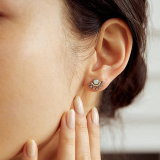 Close-up of a woman's ear wearing a decorative earring with a blurred background