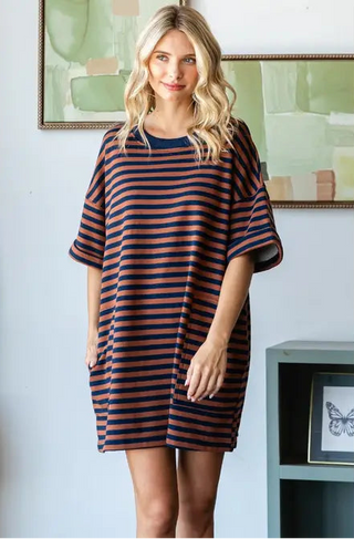 Woman wearing a striped dress in a room with a painting on the wall.