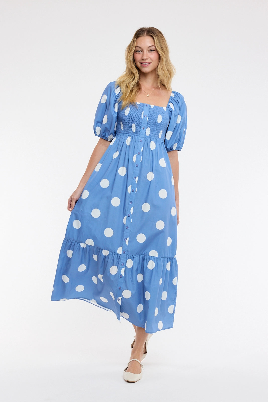 women wearing a blue and white polka dot maxi dress on a white background.