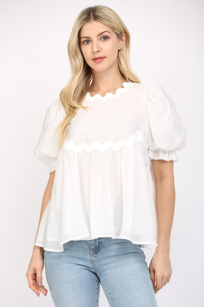 Women wearing a white flowy blouse and blue jeans on a white background. 