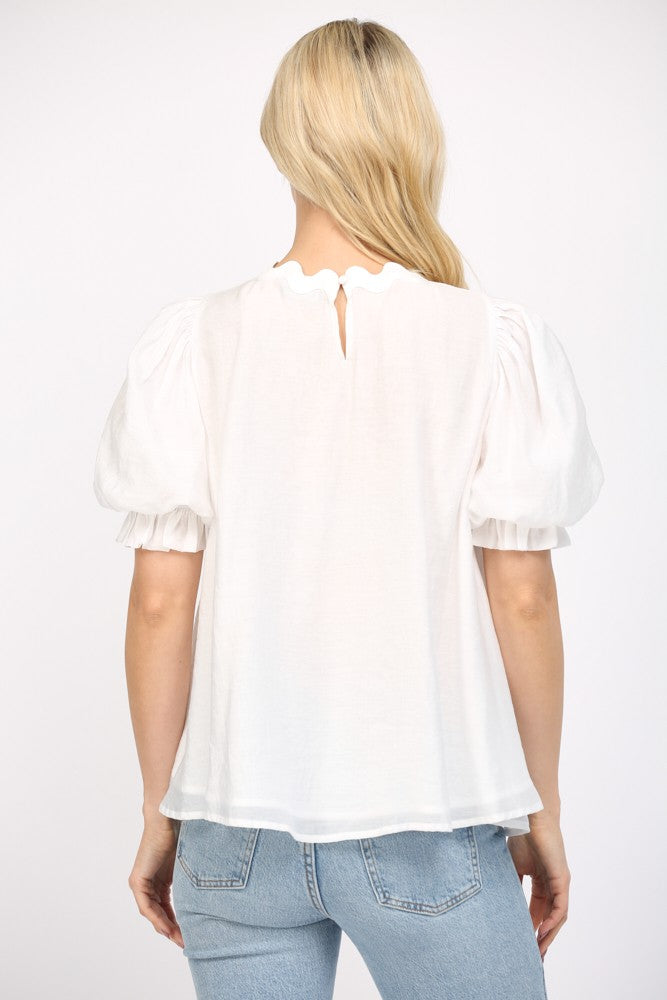 Women wearing a white flowy blouse and blue jeans on a white background. 