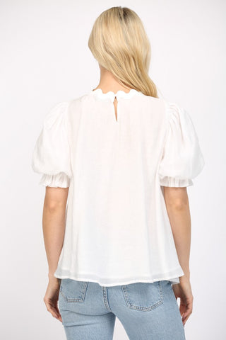 Women wearing a white flowy blouse and blue jeans on a white background. 