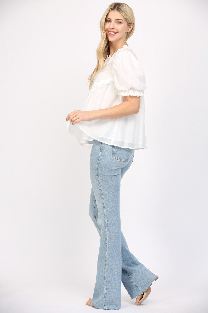 Women wearing a white flowy blouse and blue jeans on a white background. 