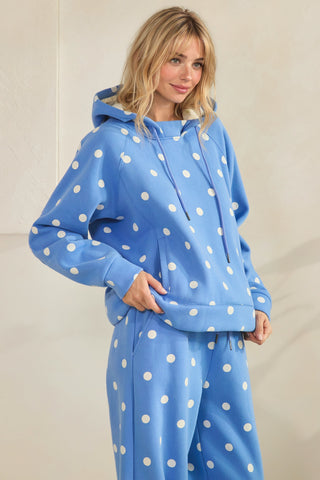 Woman wearing a blue hoodie and pants with white polka dots against a plain background