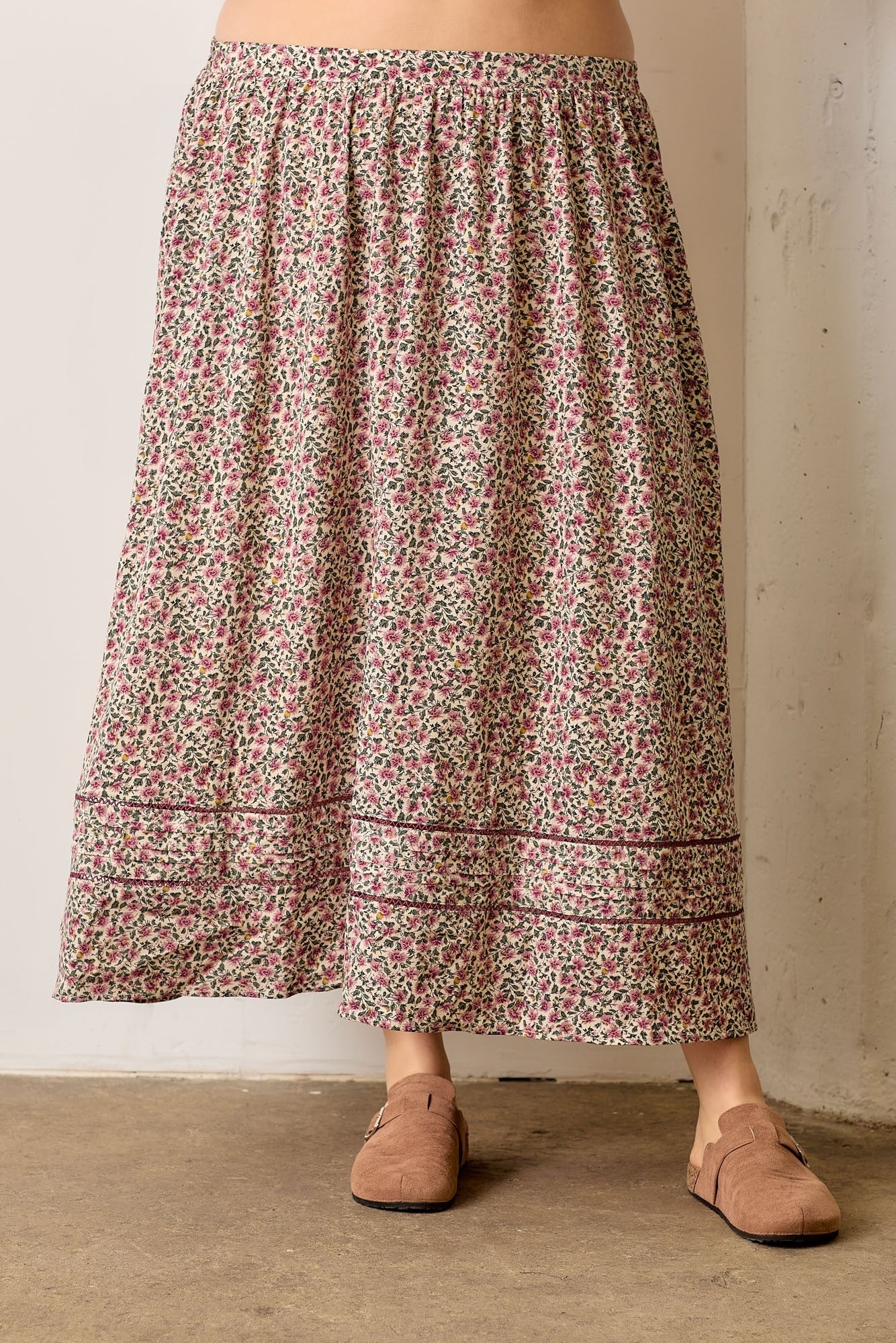 Person wearing a floral skirt with a neutral background