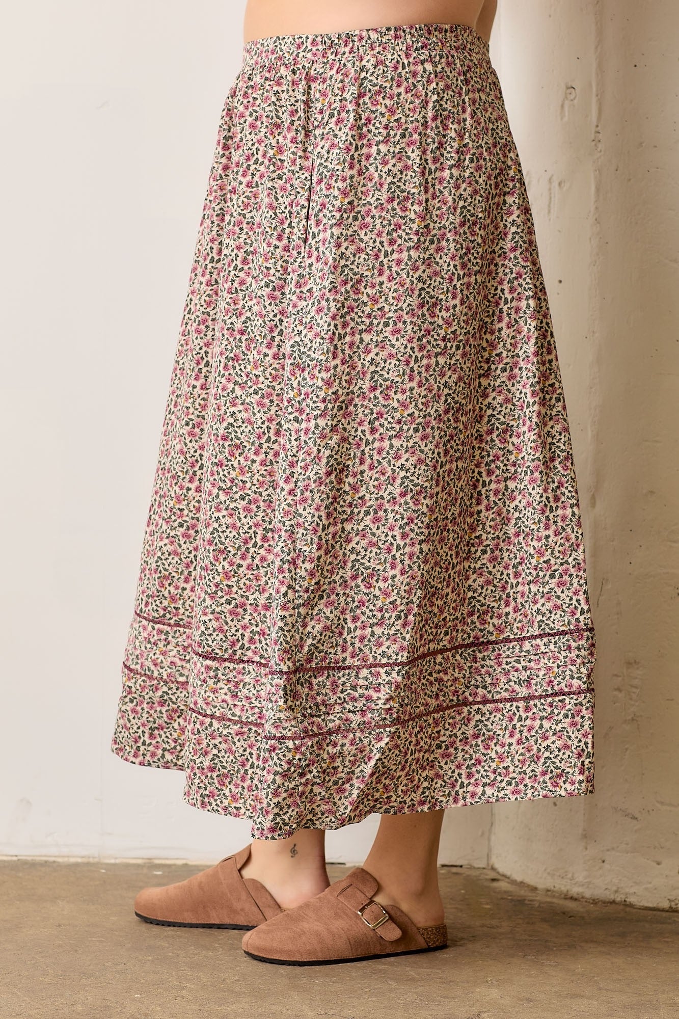 Person wearing a floral skirt with a neutral background