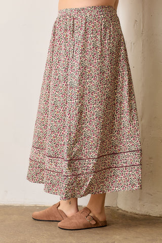 Person wearing a floral skirt with a neutral background