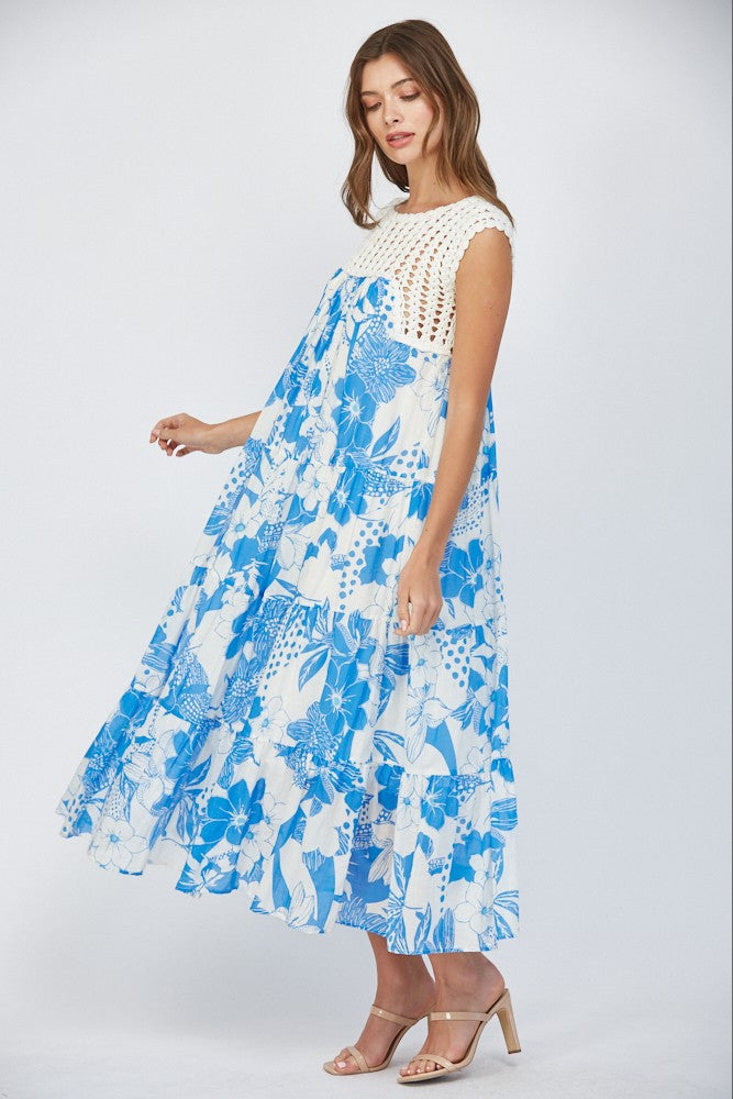 Women wearing a floral blue dress with crochet sleeves on a white background.