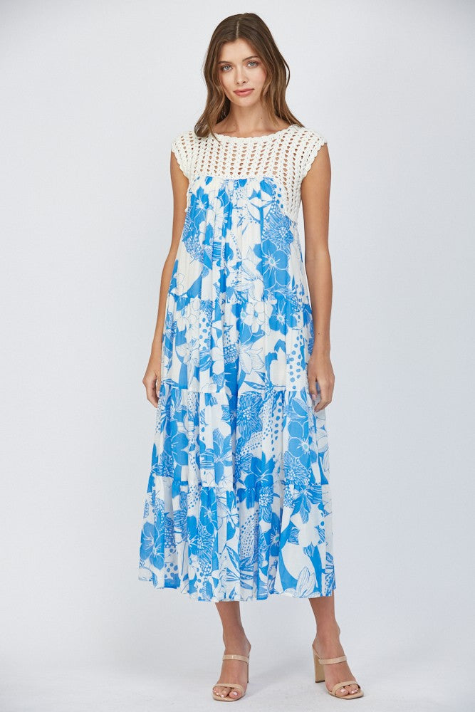 Women wearing a floral blue dress with crochet sleeves on a white background.