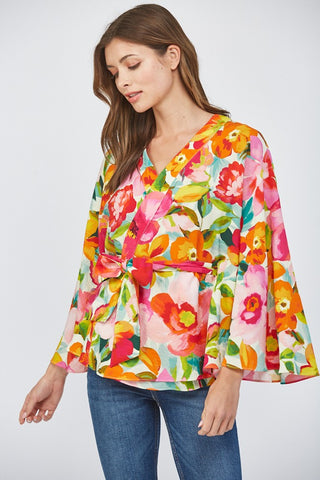 Women wearing a floral wrap top with blue jeans on a white background.