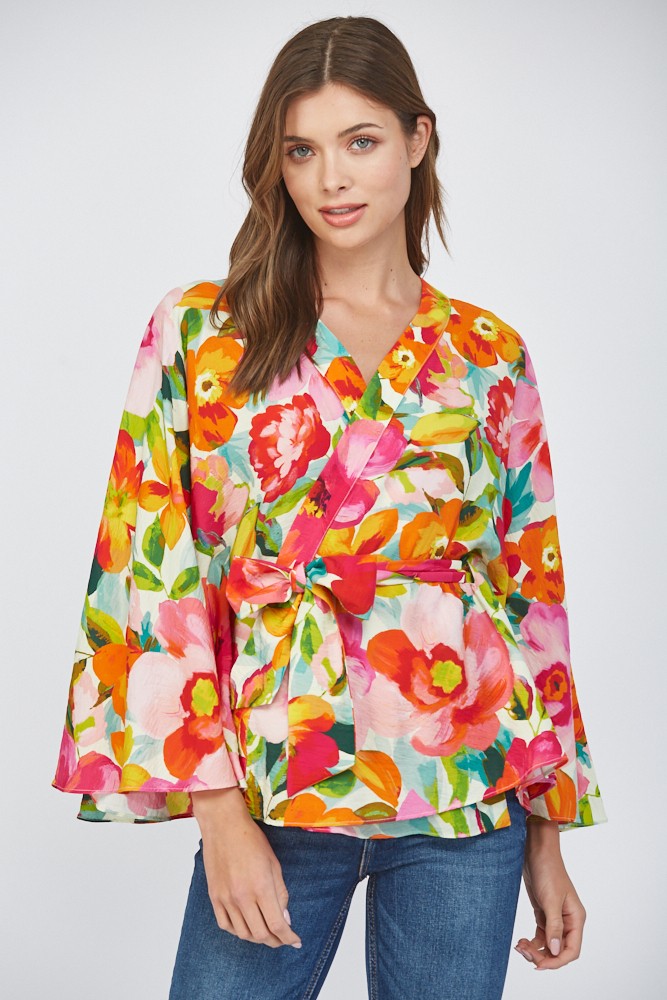 Women wearing a floral wrap top with blue jeans on a white background.