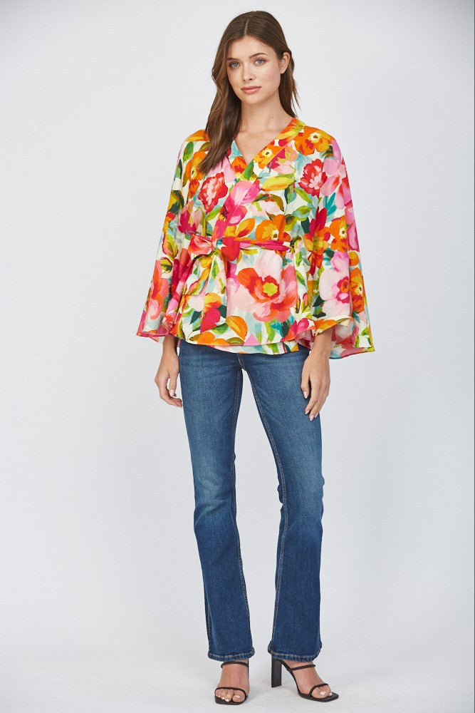 Women wearing a floral wrap top with blue jeans on a white background.