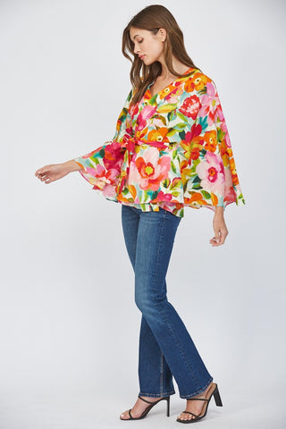 Women wearing a floral wrap top with blue jeans on a white background.