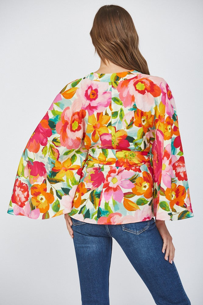 Women wearing a floral wrap top with blue jeans on a white background.