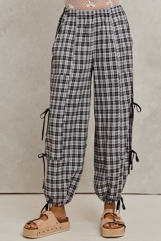 Plaid pants with lace-up sides worn by a person on a neutral background