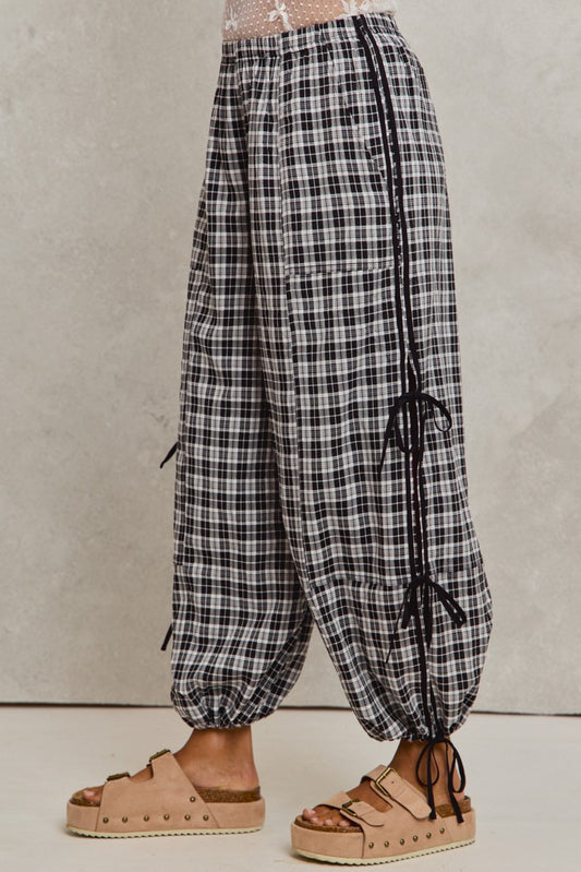 Plaid pants with drawstring details worn by a person on a plain background