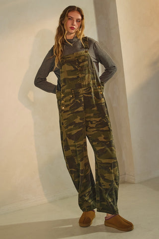 Person wearing camouflage overalls and brown shoes against a plain background