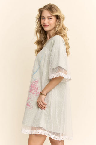 Women modelling a sage green mini dress with a lace overlay against a neutral photo backdrop.