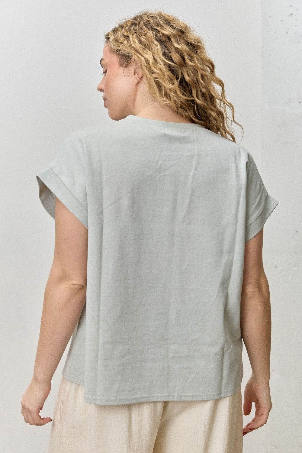 Woman wearing a light gray top against a white background