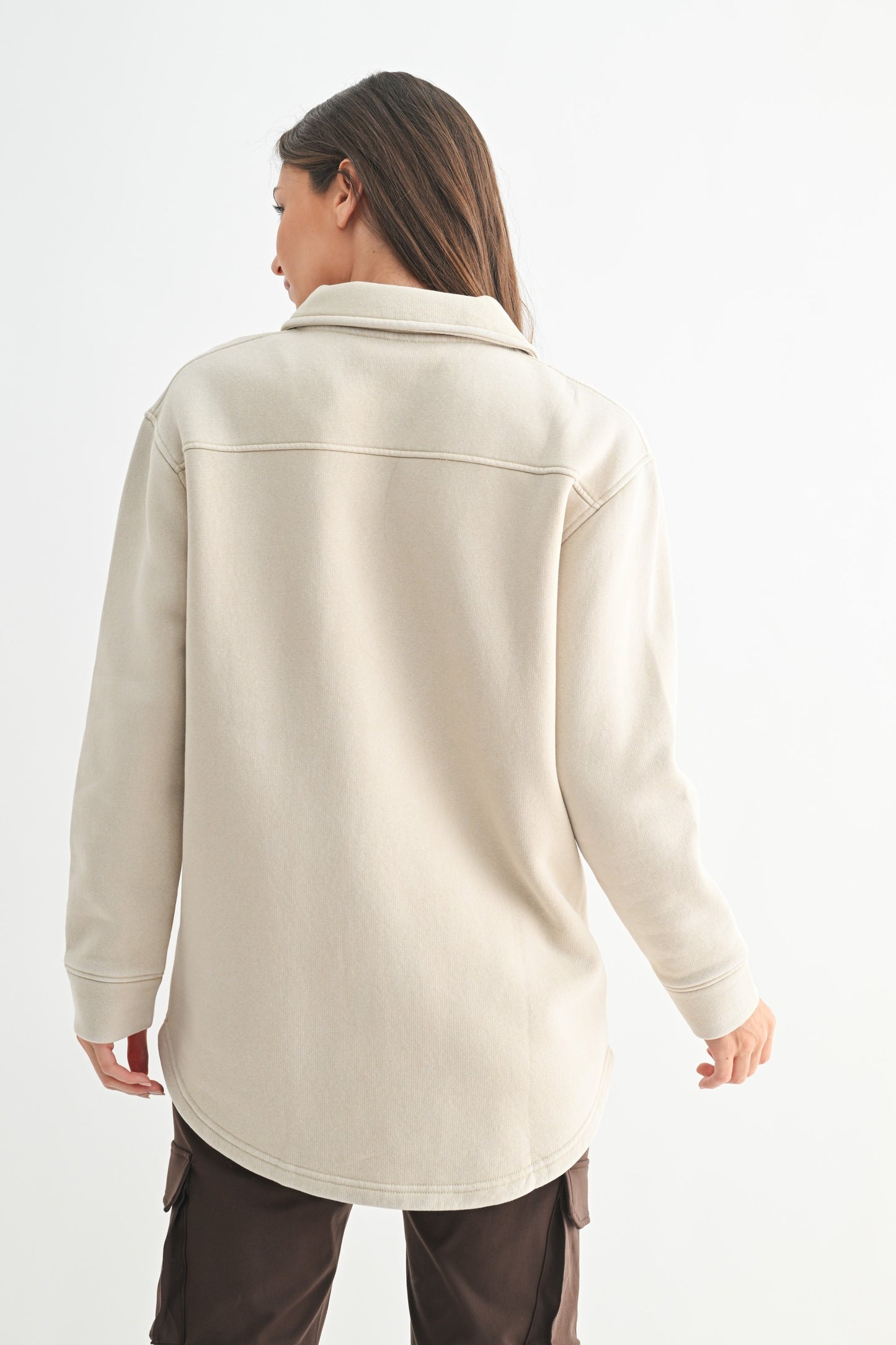 Person wearing a beige long-sleeve shirt on a white background