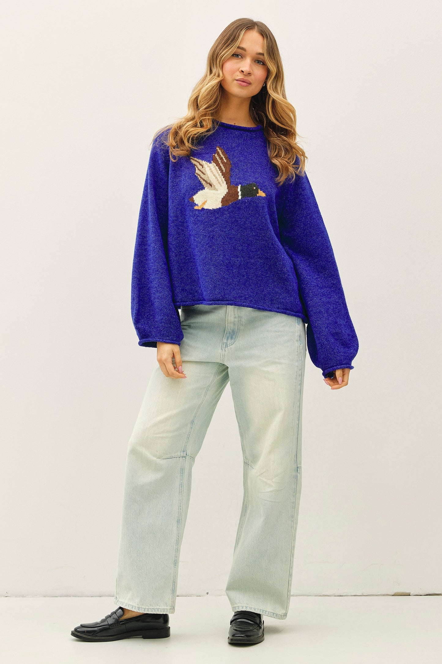 Woman wearing a blue sweater with a duck design on a white background