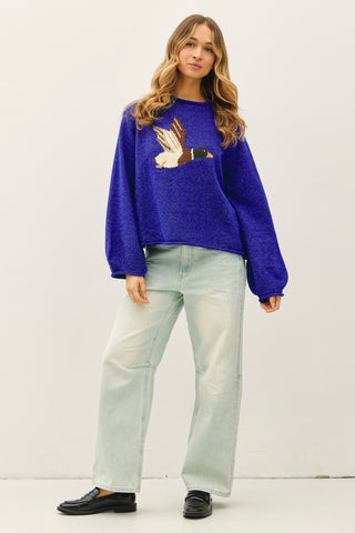 Woman wearing a blue sweater with a duck design on a white background