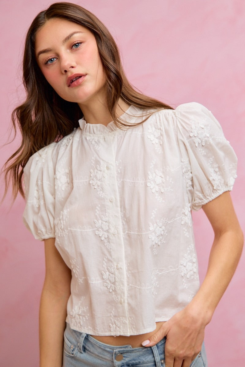 Woman wearing a white lace blouse against a pink background