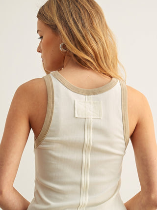 A woman shown from the back wearing a ribbed sleeveless tank top in a warm off-white or cream color, with beige trim along the shoulder straps and neckline.