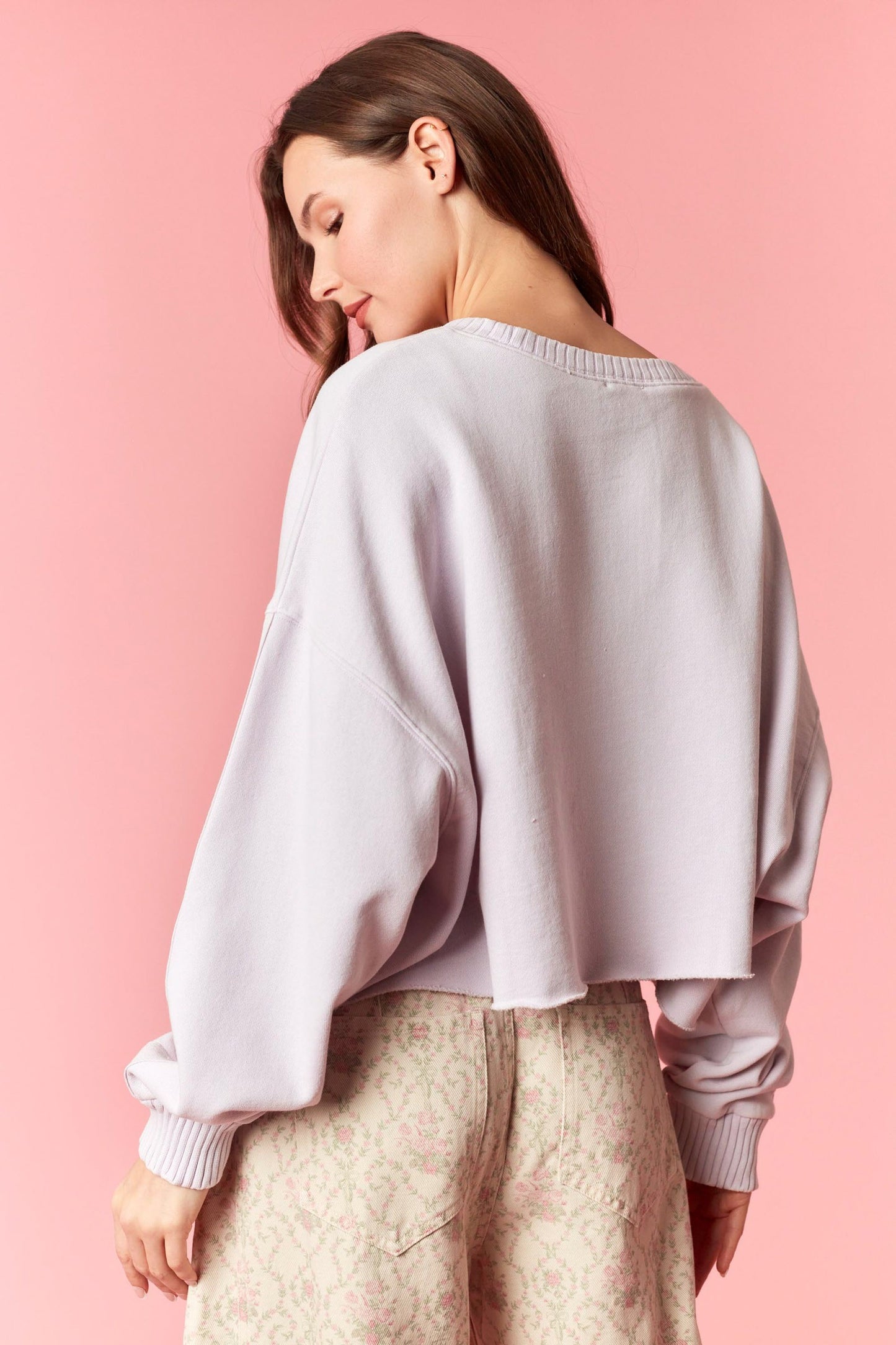 Woman wearing a light purple sweater against a pink background