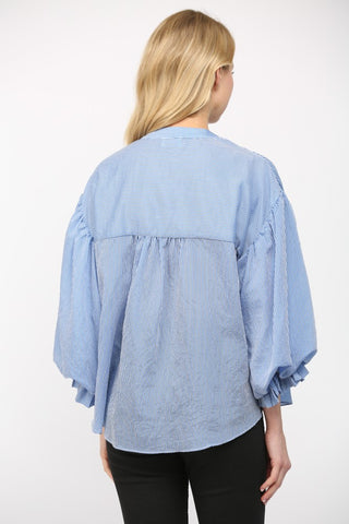 Women wearing a blue stripe blouse with black jeans on a white background.