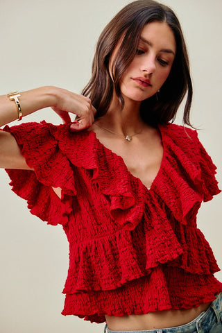 Woman wearing a red ruffled top against a neutral background
