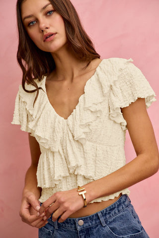 Woman wearing a white ruffled top with a pink background