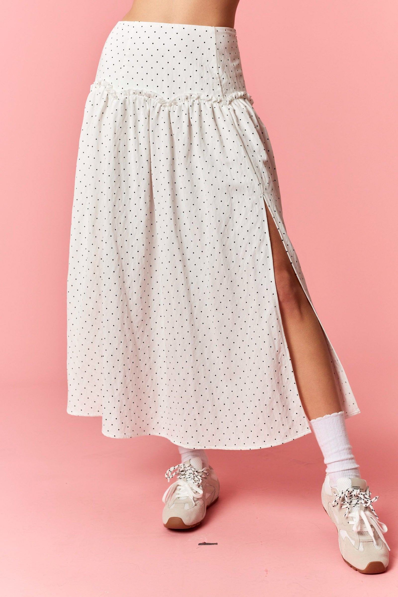 White polka dot skirt with a slit on a pink background