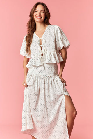 Woman wearing a white floral dress on a pink background