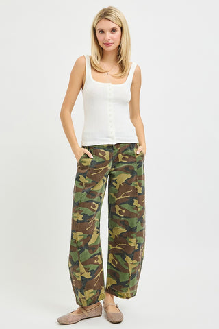 Woman wearing a white tank top and camouflage pants on a white background