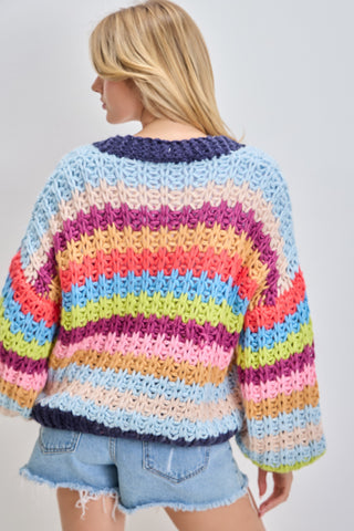 Person wearing a colorful striped sweater against a plain background
